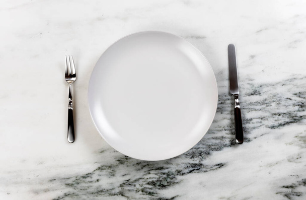 Kolacja z czystym talerzem, nożem i widelcem na marmurowym stole   - Zdjęcie, obraz