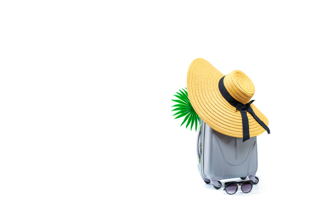 Zeeachtergrond. Reisaccessoires met koffer, strohoed, palmbladeren in minimaal reisconcept geïsoleerd op witte achtergrond. Rustige strand scene met kopieerruimte. - Foto, afbeelding