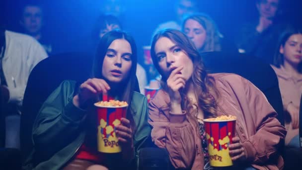 Nuoret naiset syövät välipalaa elokuvissa. Söpö tyttöystäviä rentouttava popcorn - Materiaali, video
