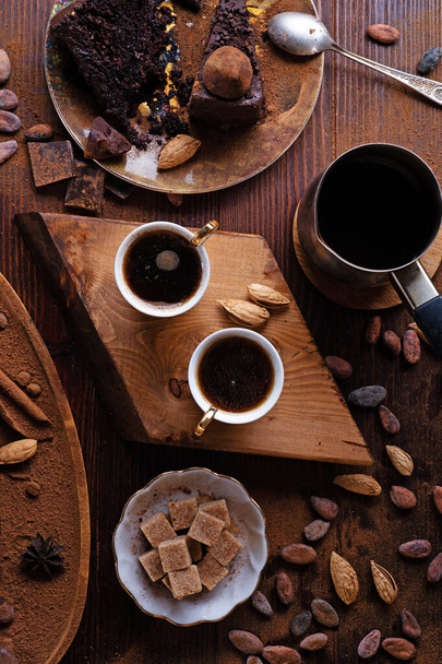  delicious chocolate truffles cakes with  cups of coffee served at dark brown wooden table . life style concept. flat lay - Foto, imagen