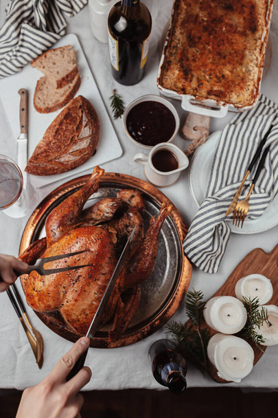 Festive dinner Thanksgiving Day, Christmas dish. Holiday season, celebration with family. Festive table setting. roasted turkey, bread, potato gratin, red wine. Candles, utensils. November, December. - Photo, image