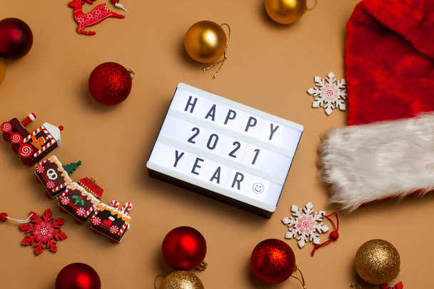 Banner con inscripción Happy 2021 Year on interior lightbox with Santa 's hat and Christmas balls and little toy train. Tiempo de Navidad. - Foto, imagen