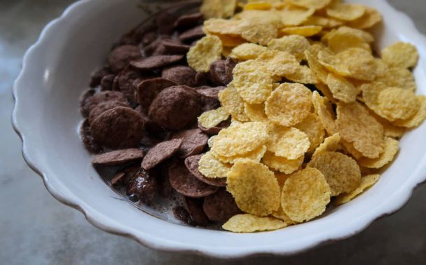 Bowl of black and yellow cereals on grey background side view - Photo, Image