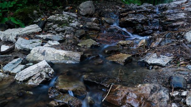 Cerca del río de montaña fluye entre pintorescas piedras de verano. Rocas en las montañas con agua fluyendo - Foto, imagen