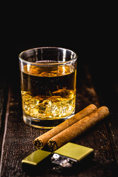 verre de whisky avec glace, sur une table en bois avec des cigares. Style de vie riche, moment de repos - Photo, image
