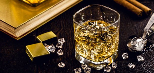 szkło kwadratowe z whisky i lodem, wysokiej jakości napój destylowany, cygaro i zapalniczka w tle. Obraz pubu, baru, restauracji lub piwnicy - Zdjęcie, obraz