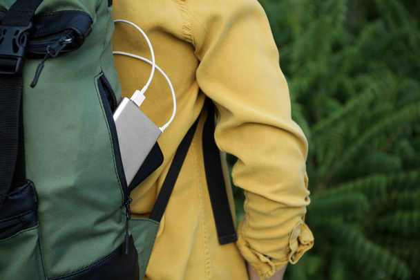 Woman with charging smartphone in backpack outdoors, closeup - Fotografie, Obrázek