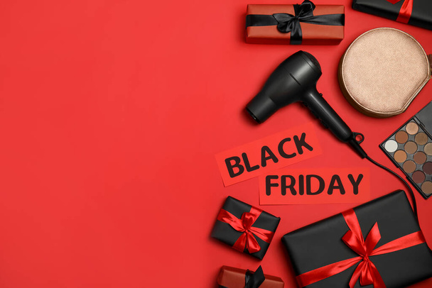 Gift boxes, cosmetics, bag, hairdryer and phrase Black Friday on red background, flat lay. Space for text - Foto, immagini