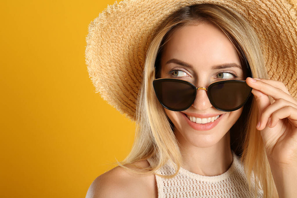 Beautiful woman in stylish sunglasses on yellow background, closeup. Space for text - Fotó, kép