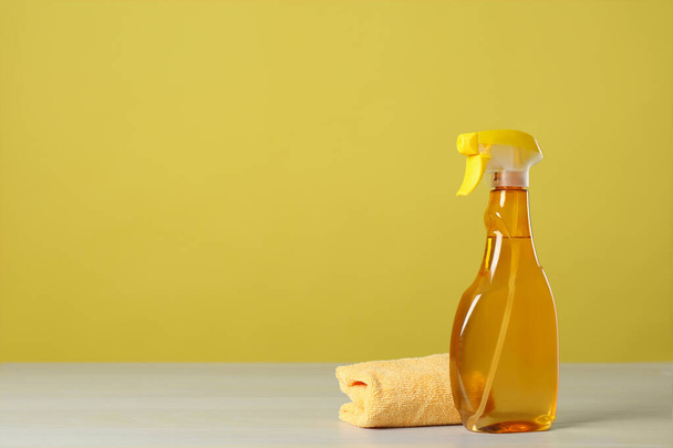 Bottle of cleaning product and microfiber cloth on light table. Space for text - Fotoğraf, Görsel