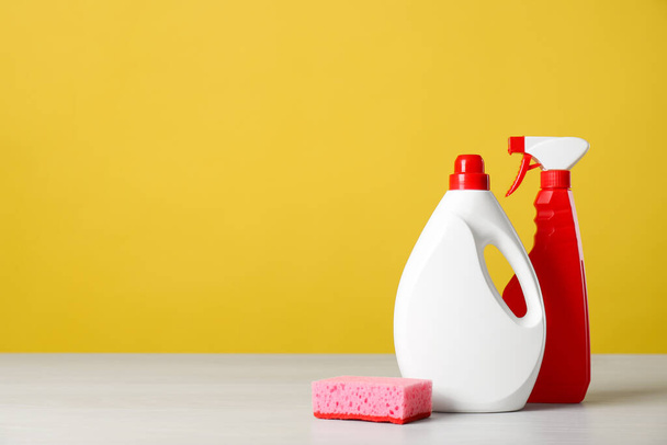 Bottles of cleaning products and sponge on light table. Space for text - Fotoğraf, Görsel