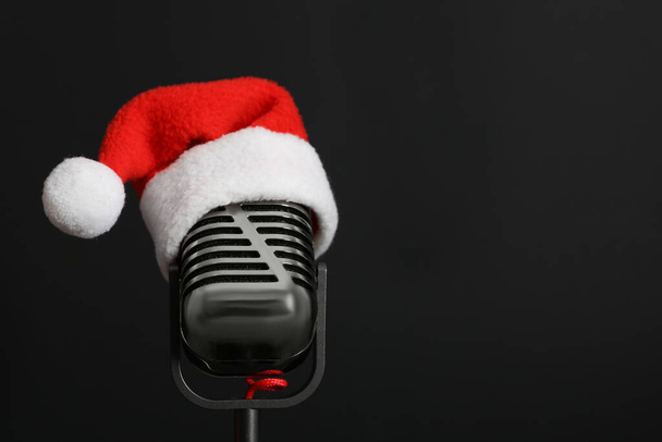 Retro microphone with Santa hat on black background, space for text. Christmas music - Photo, Image