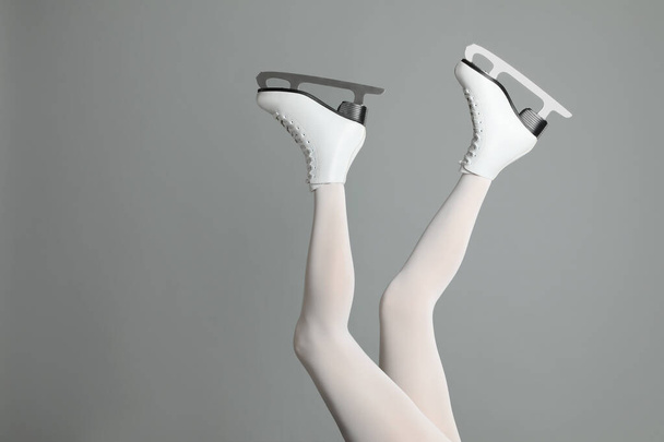 Woman in elegant white ice skates on grey background, closeup of legs. Space for text - Foto, Bild