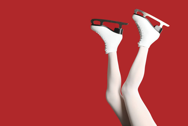 Woman in elegant white ice skates on red background, closeup of legs. Space for text - 写真・画像