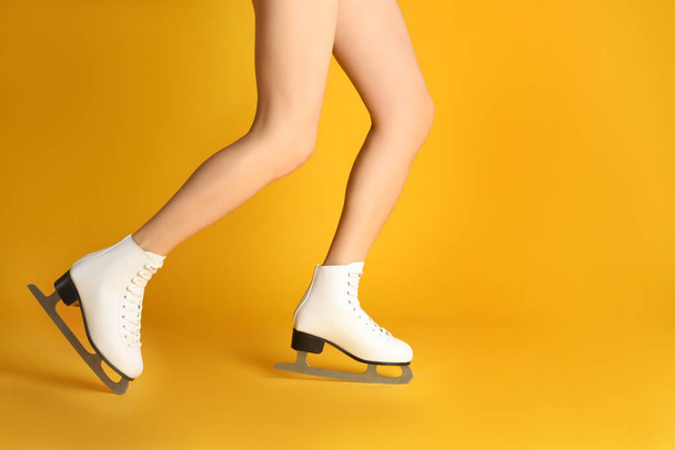 Woman in elegant white ice skates on yellow background, closeup of legs. Space for text - 写真・画像