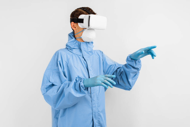 doctor in a medical mask and uniform to protect against coronavirus, using virtual reality glasses in medicine. Modern technologies, medicine - Foto, afbeelding