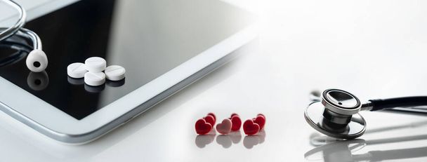 sztetoszkóp és gyógyszer tabletta és rózsaszín piros szív és tabletta számítógép tele orvostudomány egészségügyi koncepció fehér alapon - Fotó, kép