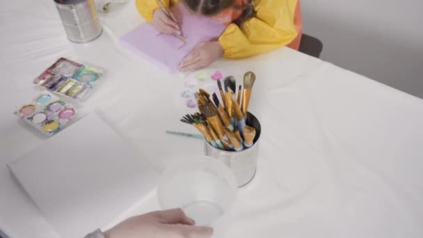 művész festi az asztalt ecsetekkel és palettával - Felvétel, videó
