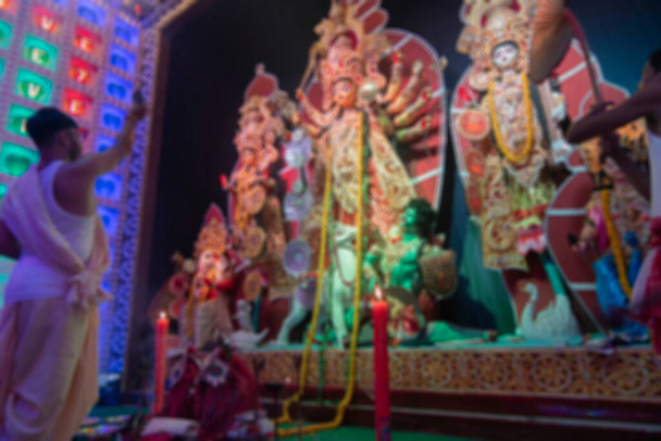 Zamazany obraz hinduskiego purohita bengalskiego pokazujący czczenie i bogini Durga lustro, po zakończeniu jej opatrunek, sondhya aarti strzał w nocy w kolorowe światło. - Zdjęcie, obraz