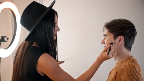Make up artist applying base on the face of male model - Záběry, video