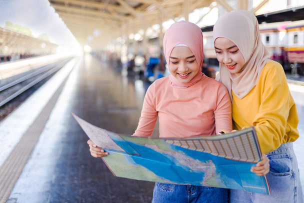 Két muszlim nő állt, és egy térképet néztek a vasúti peronon.. - Fotó, kép