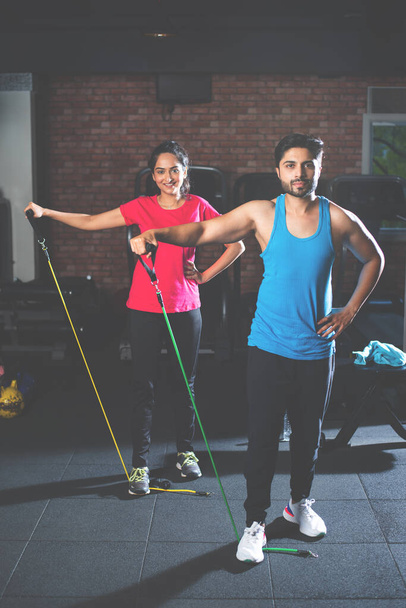 Indien asiatique jeune couple exercice avec résistance bande dans la salle de gym - Photo, image