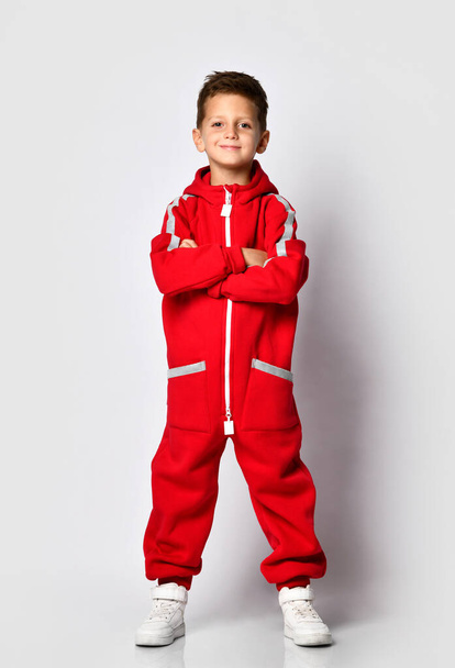 Boy in red warm jumpsuit showing victory gesture - Foto, afbeelding