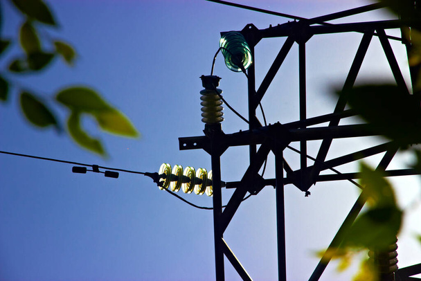 Yalıtımlı ve kablolu yüksek voltajlı elektrik hattının metal kulesi güneşli bir gün. - Fotoğraf, Görsel