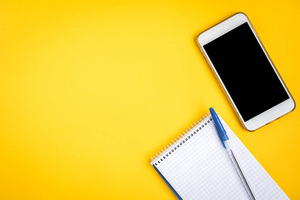Teléfono móvil y portátil sobre fondo amarillo. - Foto, imagen