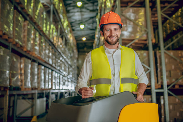 Warehouse worker in orange helmet working and looking positive - Foto, Imagem