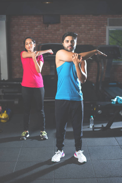 deportivo indio asiático joven pareja estiramiento en gimnasio post ejercicio para refrescarse, mejorar la flexibilidad - Foto, Imagen