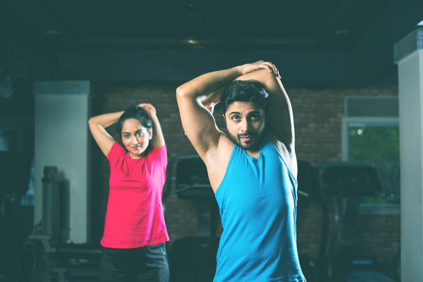 Sportif Hintli genç çift, serinlemek ve esnekliği arttırmak için spor sonrası egzersiz yapıyor. - Fotoğraf, Görsel