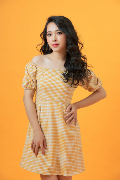 Fashionable young beautiful model posing on yellow studio background wearing dress - Фото, зображення