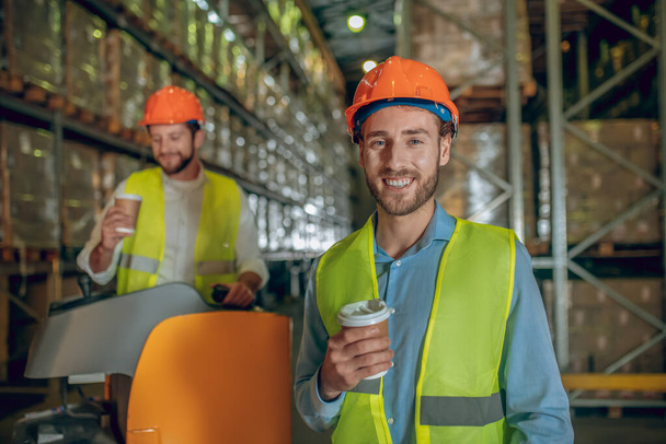 Warehouse workers in orange helmets having coffee break - Fotografie, Obrázek