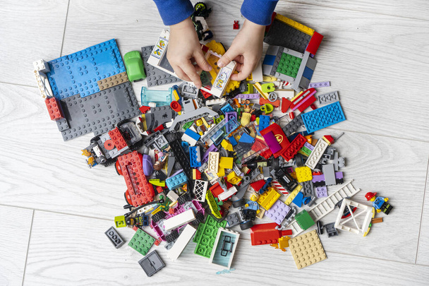 KHARKIV, UKRAINE - 22 November, 2020: Children hands playing with many Lego building kits on the floor. - Fotoğraf, Görsel