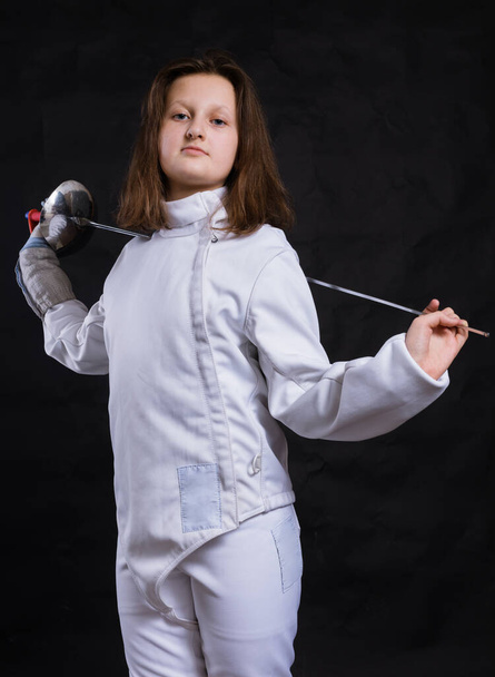 Teenage girl fencer dressed in uniform with epee and helmet - Foto, Imagen
