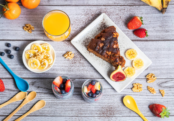 Teljes reggeli, egy pohár chia maudixel és áfonyával, banán zabpehellyel, csokoládé torta dióval, egy pohár természetes narancs és füge - Fotó, kép