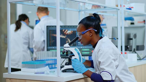 Musta biokemisti nainen istuu laboratoriossa analysoimassa verikokeita - Valokuva, kuva