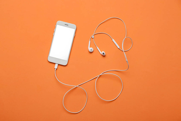 Mobile phone with earphones on color background - Foto, Imagem