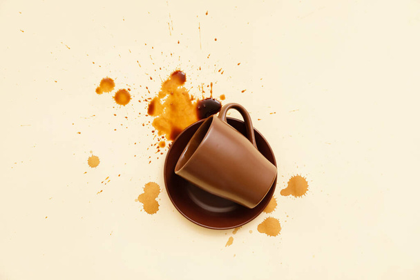 Omgekeerde kop en gemorste koffie op kleur achtergrond - Foto, afbeelding