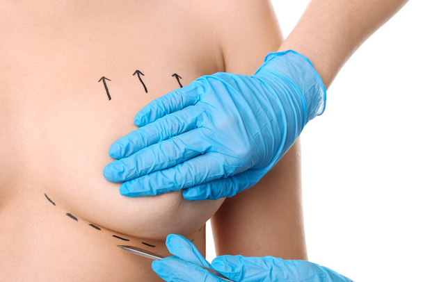 Woman and doctor with lancet on white background, closeup. Concept of breast augmentation - Photo, Image