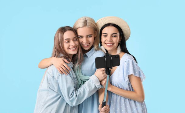 Beautiful young women taking selfie on color background - Φωτογραφία, εικόνα