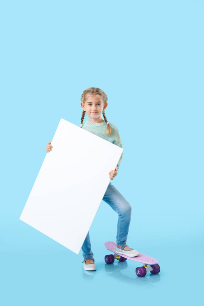 Linda niña con póster en blanco y monopatín sobre fondo de color - Foto, imagen