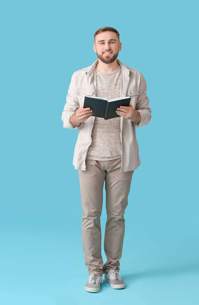 Young man reading book on color background - Photo, Image