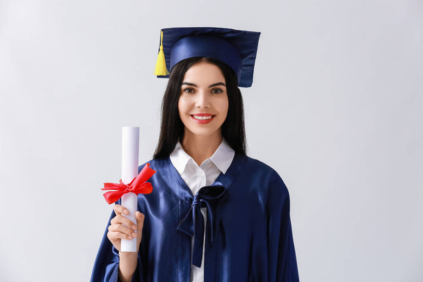 Γυναίκα απόφοιτος φοιτητής με δίπλωμα σε ελαφρύ υπόβαθρο - Φωτογραφία, εικόνα