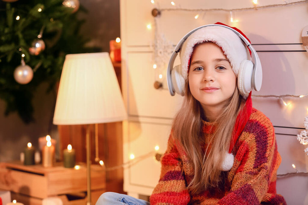 Cute little girl listening to Christmas music at home - Fotó, kép