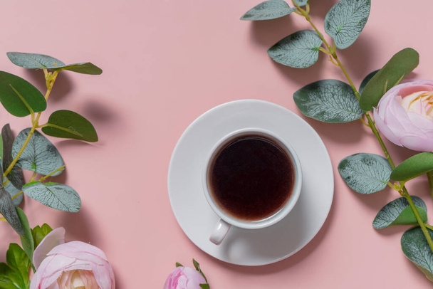 a small white coffee mug on a white saucer. espresso. flatlay. the view from the top. soft pink background with flowers. copyspace - Zdjęcie, obraz