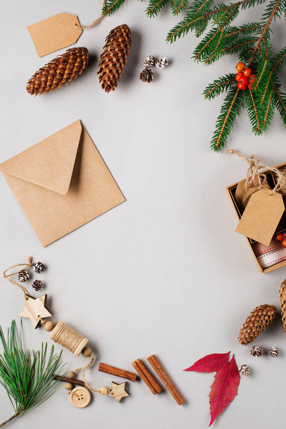Fond de vacances de Noël avec décorations en bois naturelles, cônes de pin, enveloppe en papier artisanal et branches sur gris. Espace de copie, vue du dessus. Concept de Noël zéro déchet. - Photo, image