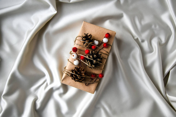 Cadeaux de Noël zéro déchet avec des décorations sur fond de soie couleur champagne. Espace de copie. Cadeau écologique emballé avec des étiquettes de carton artisanal. Nouvel an - Photo, image