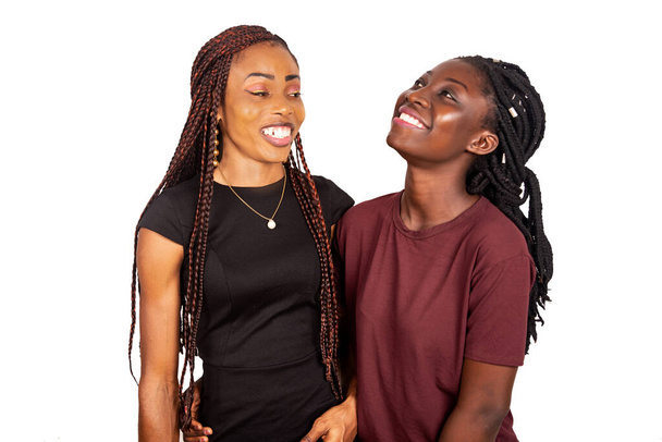 δύο νεαρά όμορφα κορίτσια που στέκονται μαζί χαμογελώντας σε απομονωμένο φόντο - Φωτογραφία, εικόνα